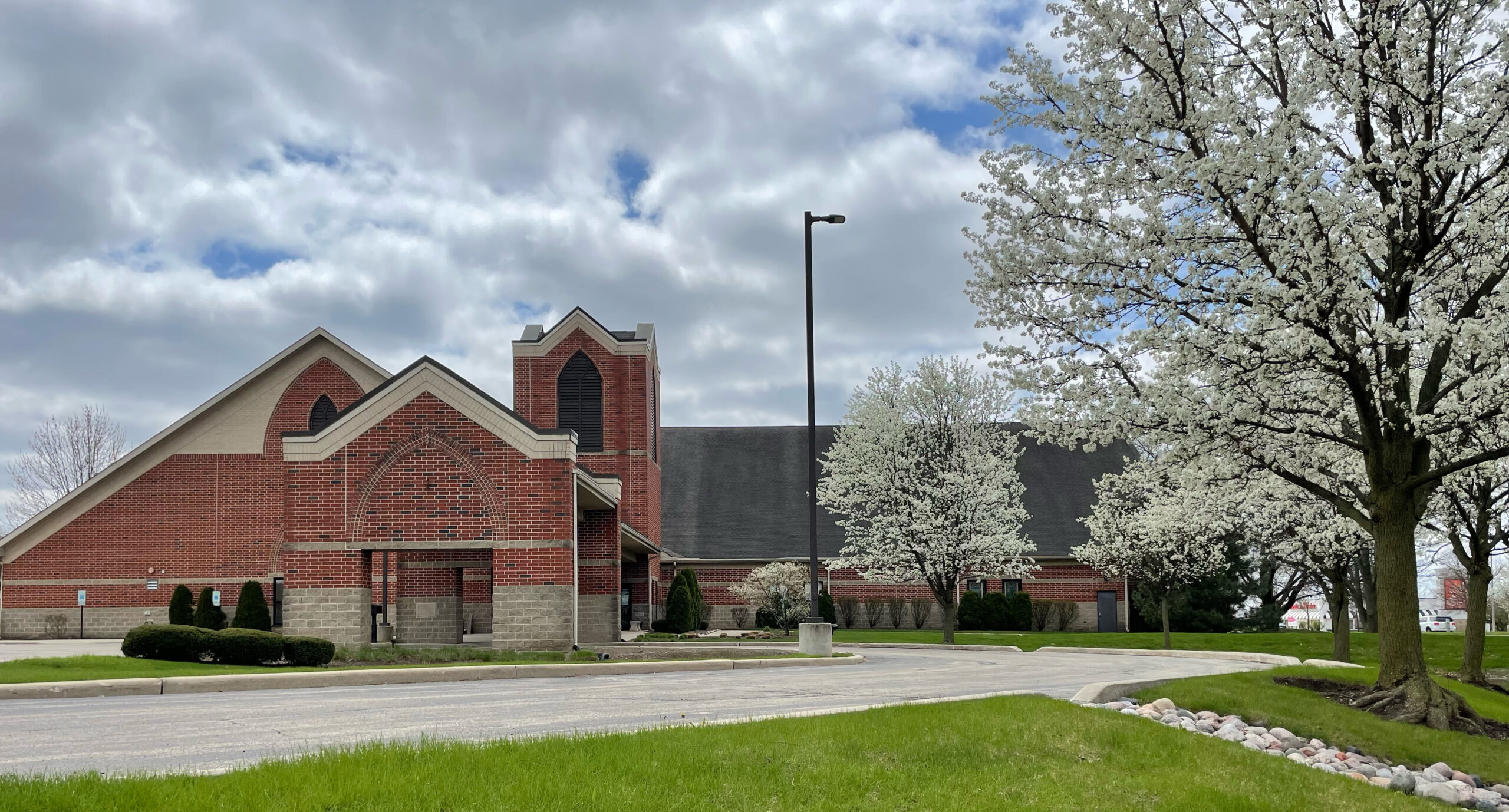 front of the church building with trees blooming in the parking lot