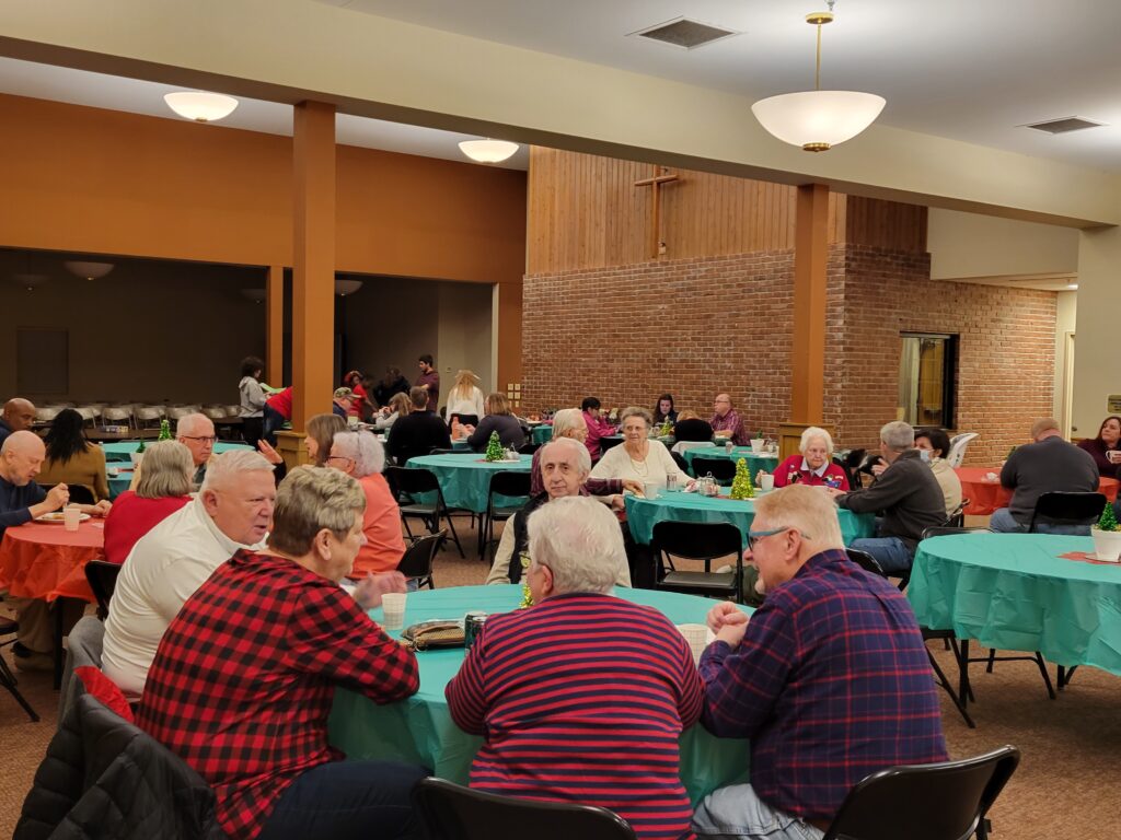 8 round tables of people eating at Christmas Party